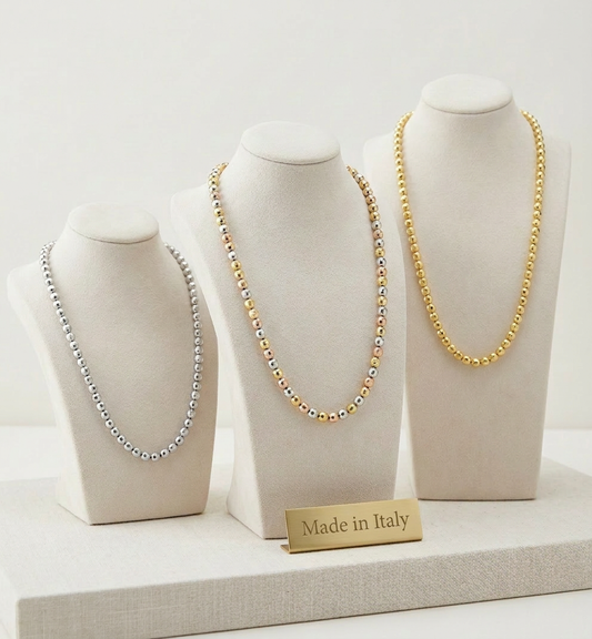 Three necklaces on mannequin heads with 'Made in Italy' label on a light background