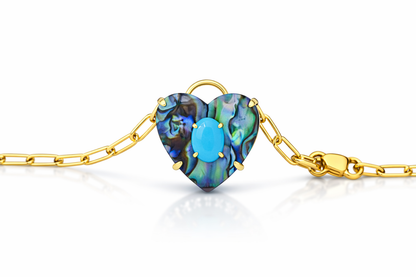 Gold bracelet with a heart-shaped abalone shell and turquoise stone on a white background