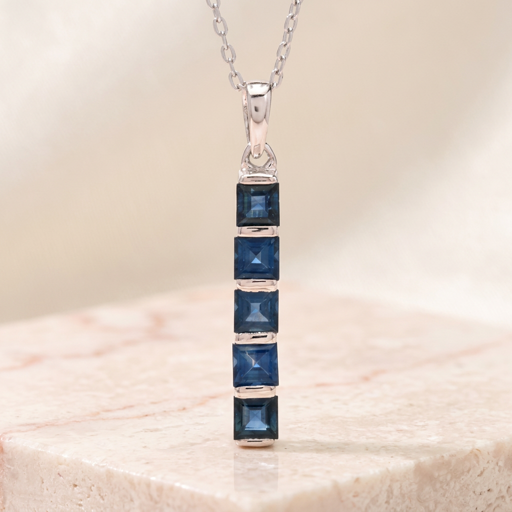 silver necklace featuring blue sapphires on a neutral background