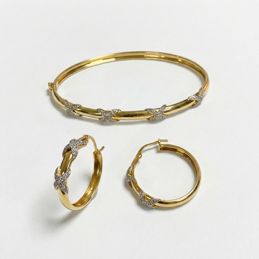 Gold and diamond bracelet and hoop earrings on a light gray background