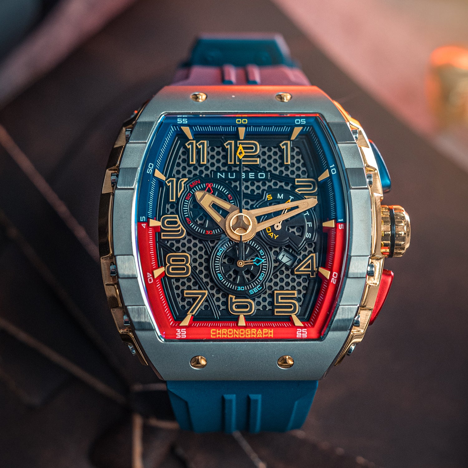 Luxury watch with blue strap and multicolored face on a blurred background