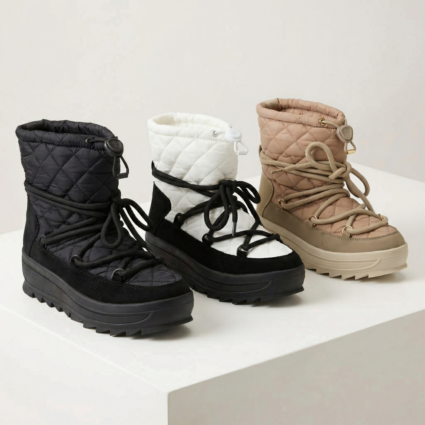 Three winter boots on a display table with a soft white background