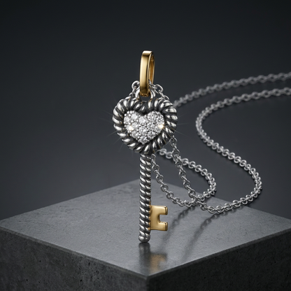 Silver key-shaped pendant with heart detail on a chain against a dark background