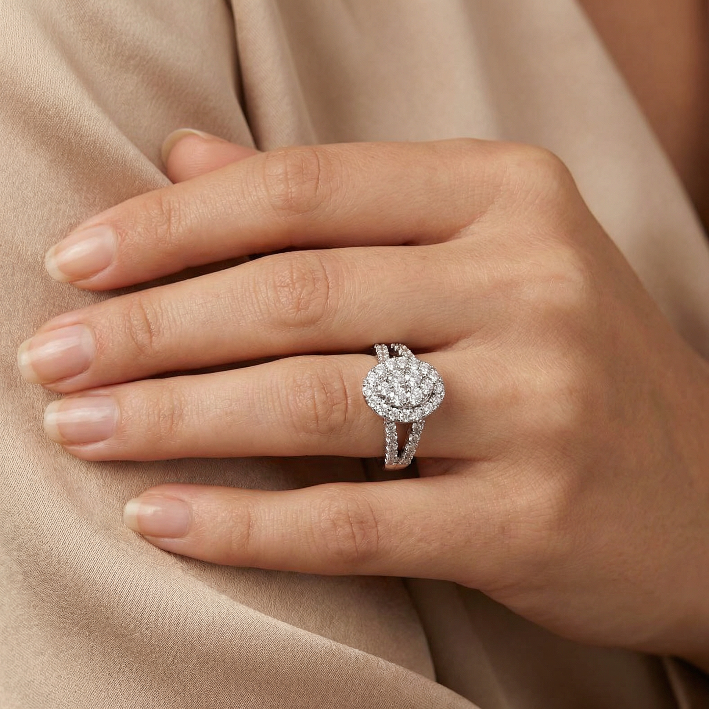 Close-up of a hand wearing a diamond ring on a beige fabric background